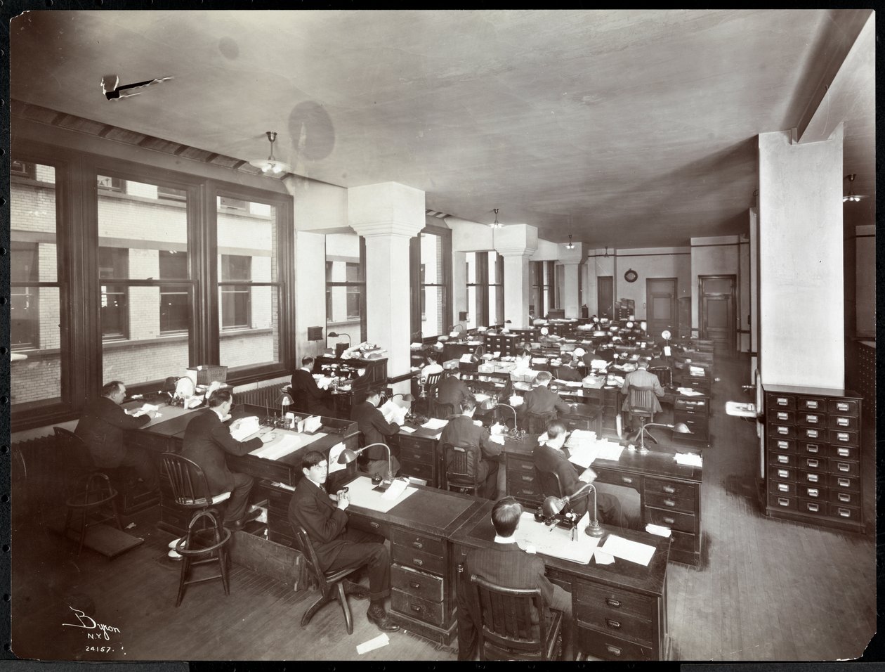 Uomini e una donna che lavorano a scrivanie in un ufficio della Metropolitan Life Insurance Co. in 23rd Street e Madison Avenue, New York, 1907 da Byron Company