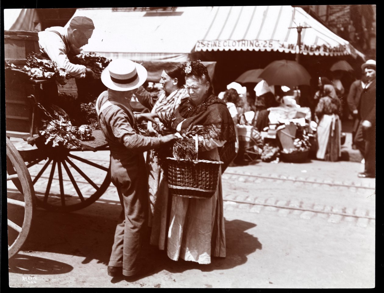 Veduta di donne che comprano verdure da un venditore ambulante per strada, New York, 1898 da Byron Company