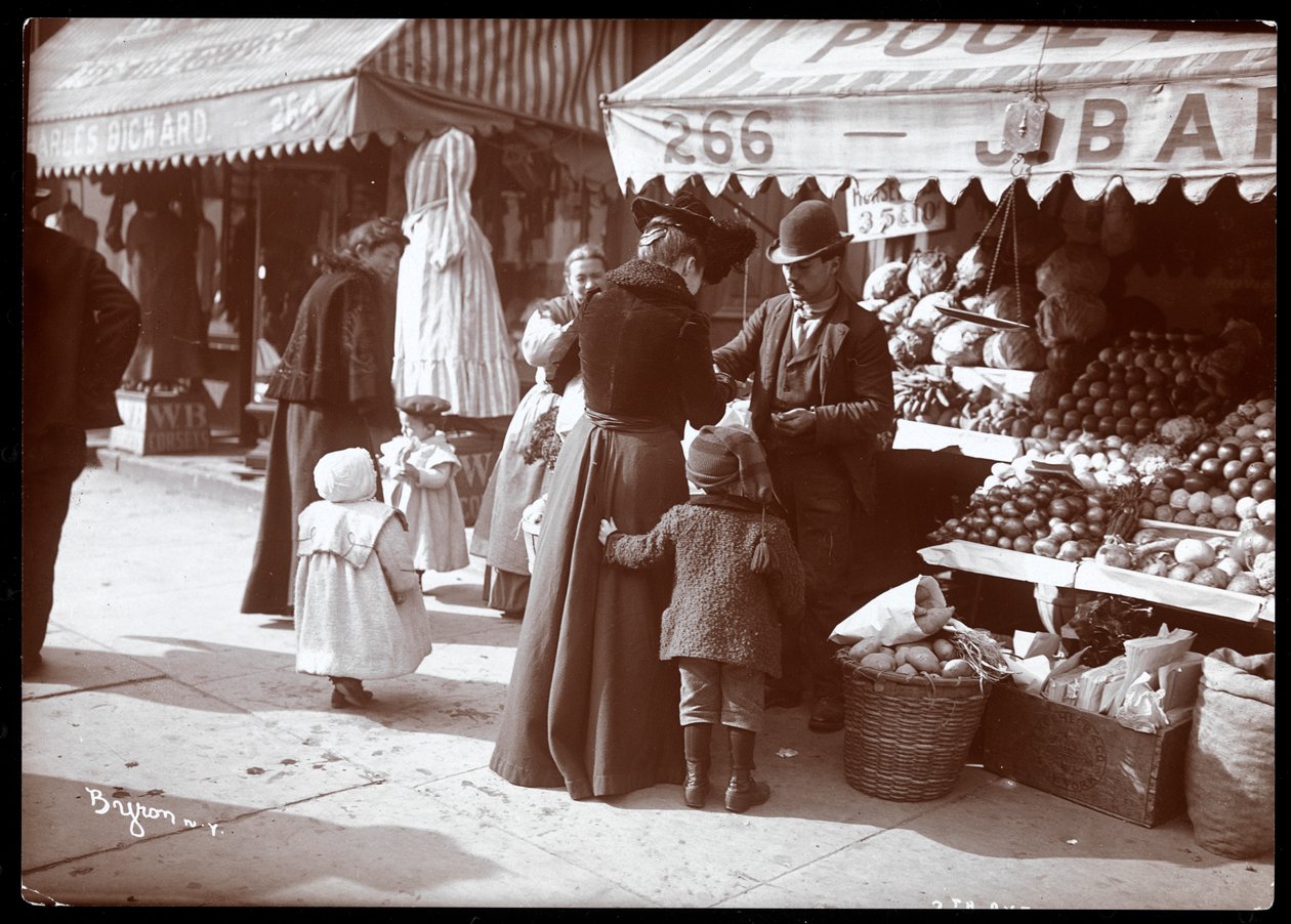 Veduta di donne con bambini che fanno acquisti a un banco di frutta e verdura al 266 7th Avenue, New York, c.1900 da Byron Company