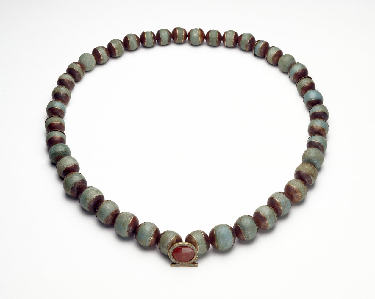 Cilindro di faience e collana con pendente in oro, turchese e corniola a forma di anello shen, il segno dell