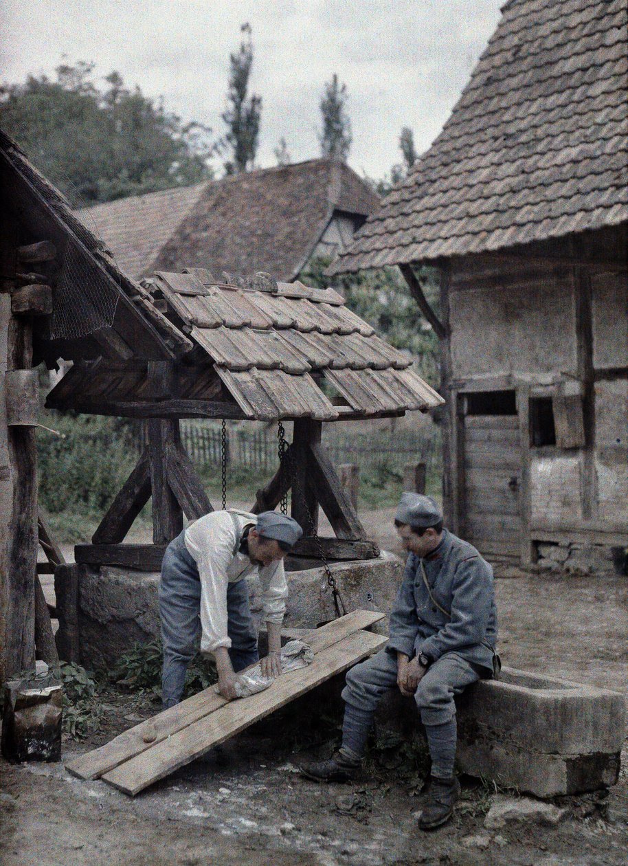 Due soldati francesi si occupano del bucato usando tavole sistemate sulla vasca di una fontana vicino a una fattoria nella città di Gildwiller, Dipartimento Haut-Rhin, Alsazia, Francia, 21 giugno 1917 da Paul Castelnau