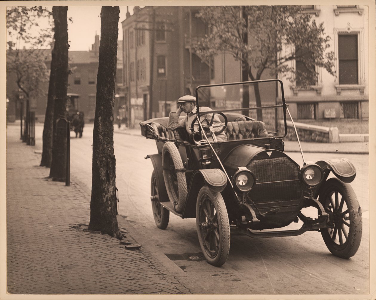 Uomo seduto in automobile su una strada non identificata da William G. Swekosky